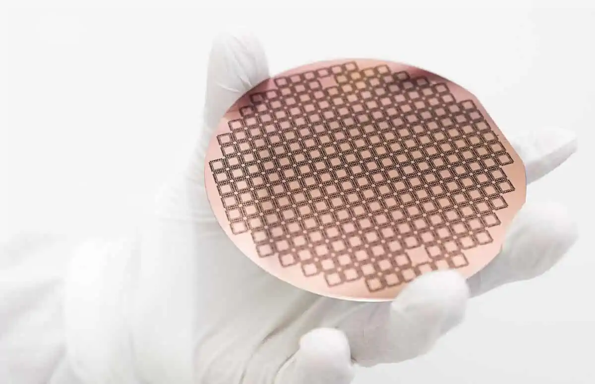 A hand holds a silicon wafer with a grid pattern of carbon nanofibres.