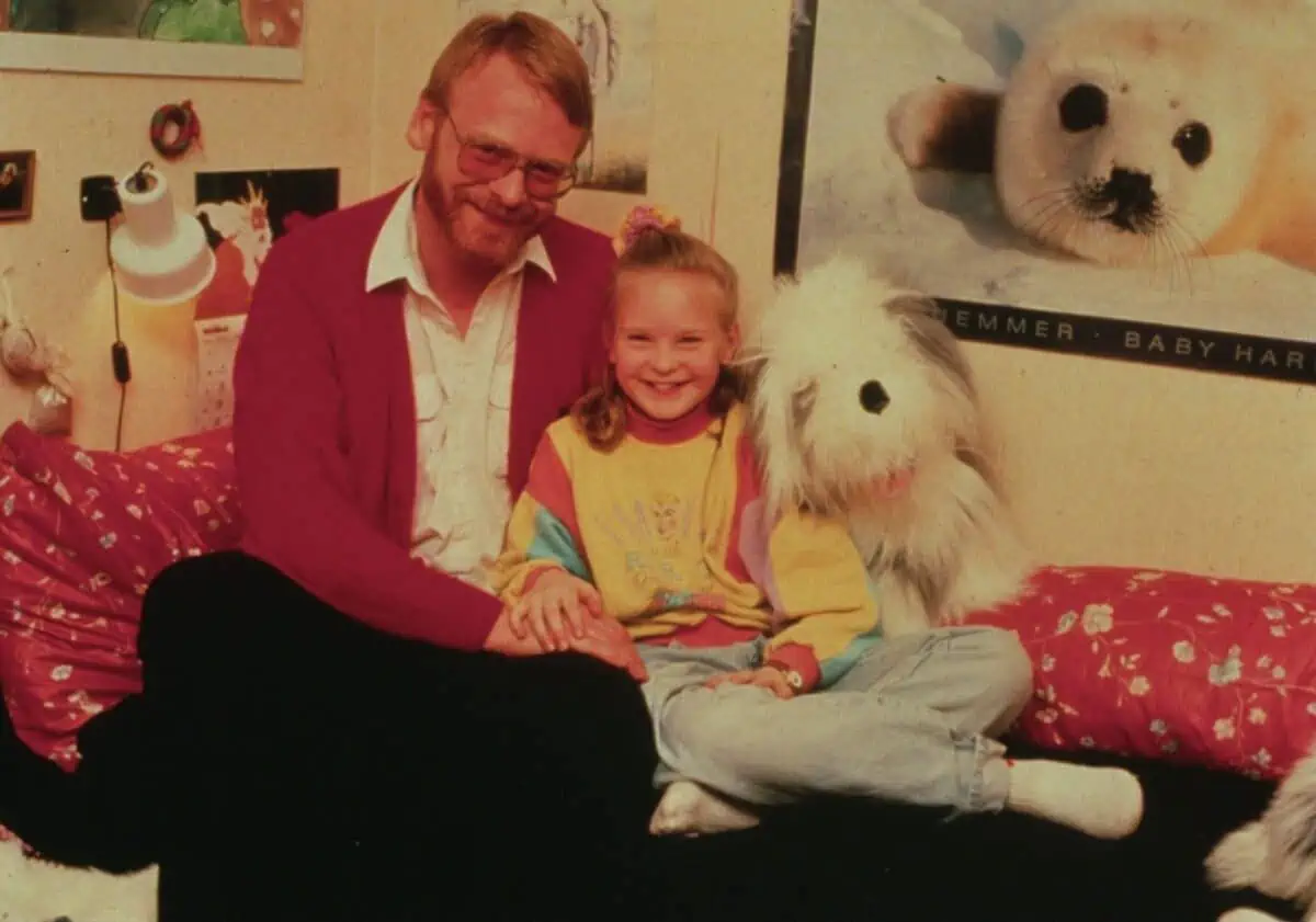 Fading color photograph of father and daughter on her bed.