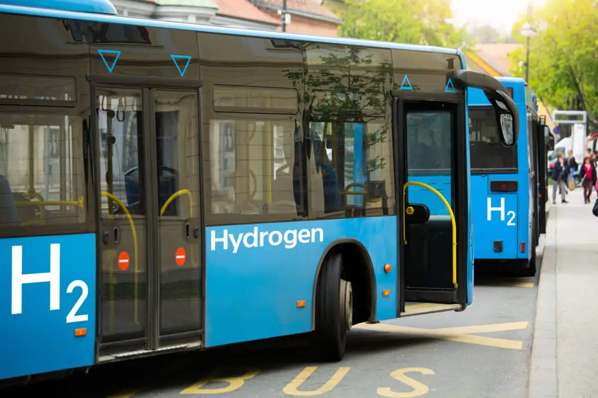 Two buses in city traffic marked with "H2 Hydrogen"